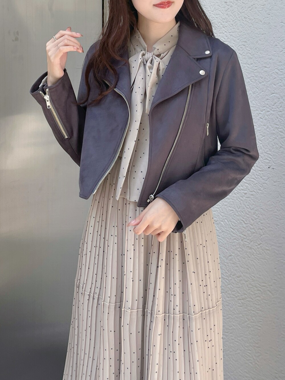 グレー系のライダースジャケット、ブラック系のブーツ、ベージュ系のワンピースを着用したレディースの秋コーディネートの4枚目の写真