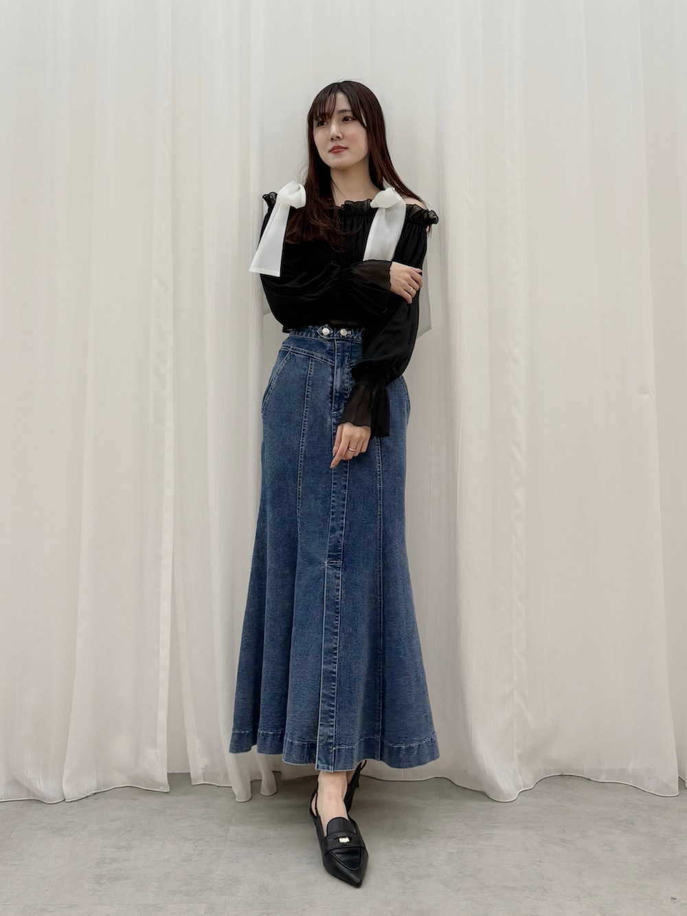ブラック系のシャツ/ブラウス、ブルー系のスカート、ブラック系のパンプスを着用したレディースの春コーディネートの2枚目の写真