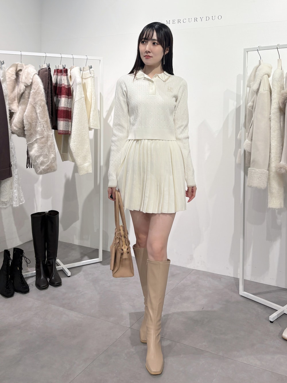 ベージュ系のハンドバッグ、ベージュ系のブーツ、ホワイト系のワンピースを着用したレディースの冬コーディネートの2枚目の写真