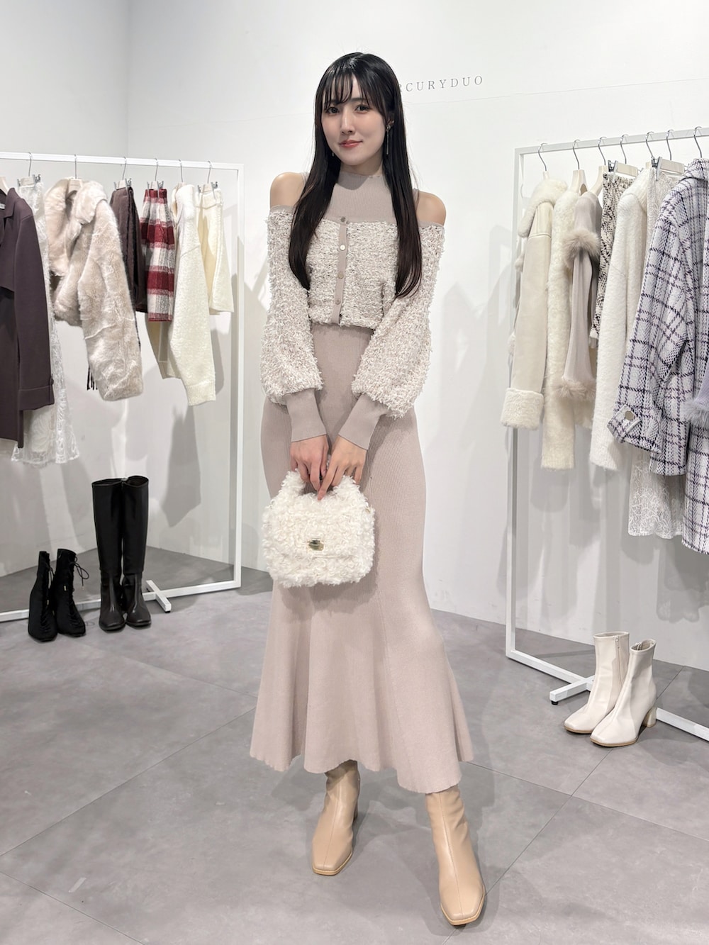 ブラウン系のチェスターコート、ピンク系のワンピース、ベージュ系のブーツを着用したレディースの冬コーディネートの4枚目の写真