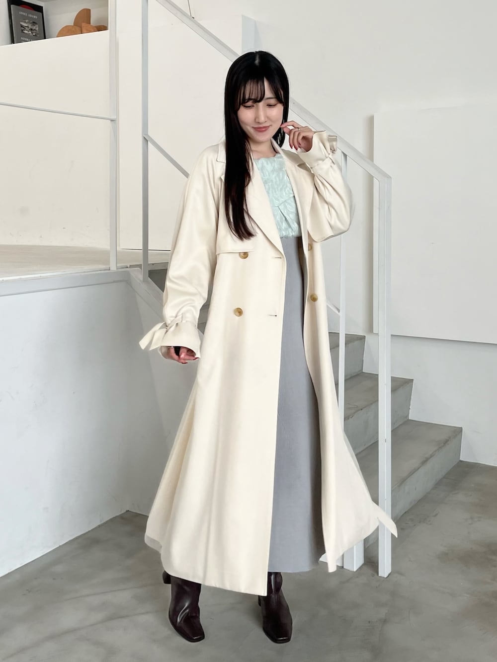 ブラウン系のブーツ、ホワイト系のトレンチコート、グリーン系のワンピースを着用したレディースの春コーディネートの2枚目の写真