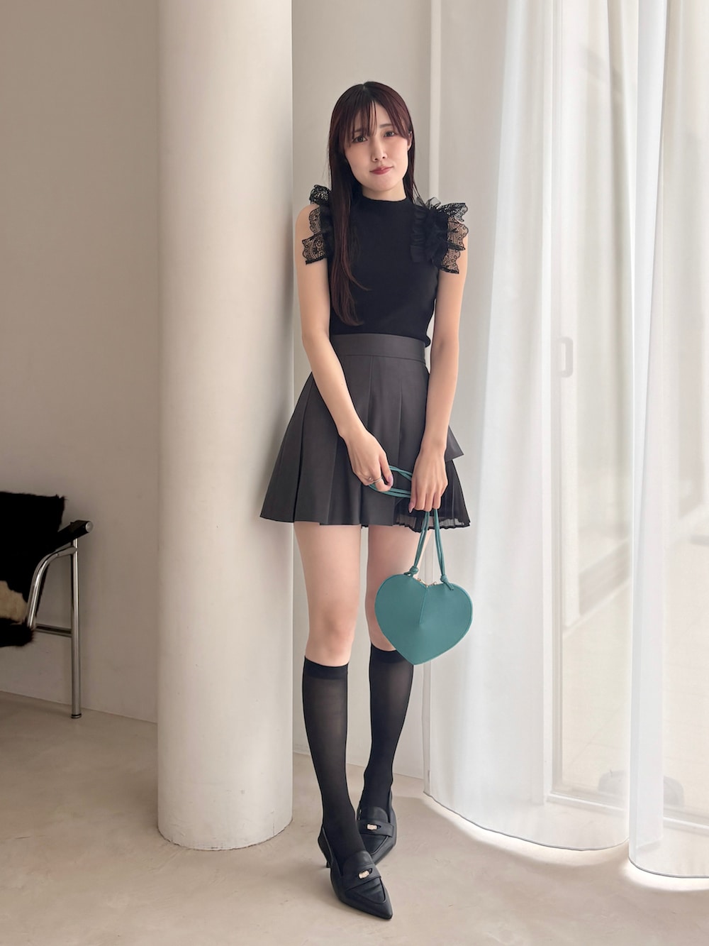 ブラック系のパンプス、グレー系のスカート、ブラック系のニット/セーターを着用したレディースの春コーディネートの2枚目の写真