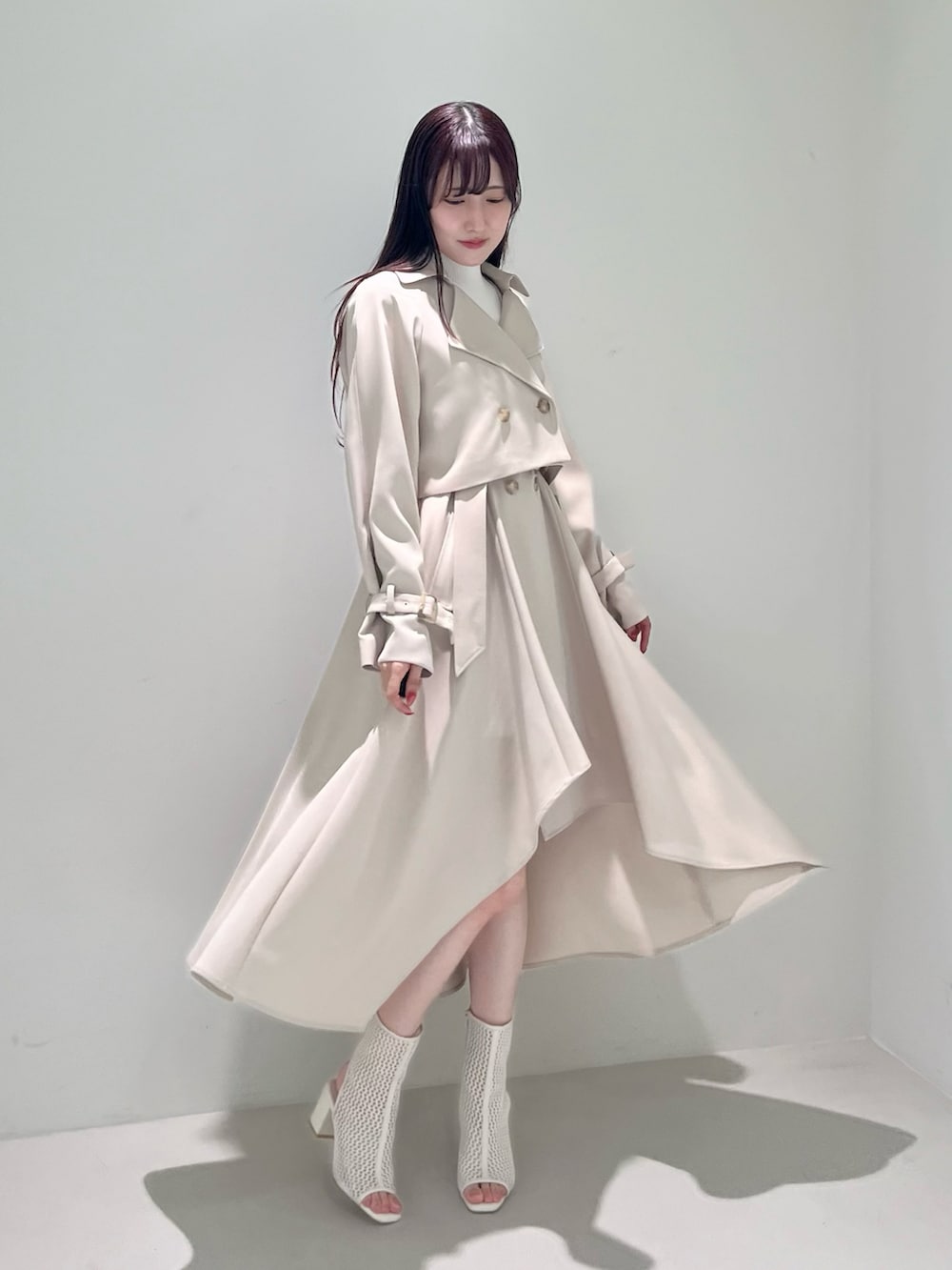 ホワイト系のブーツ、ベージュ系のトレンチコート、ベージュ系のワンピースを着用したレディースの冬コーディネートの3枚目の写真