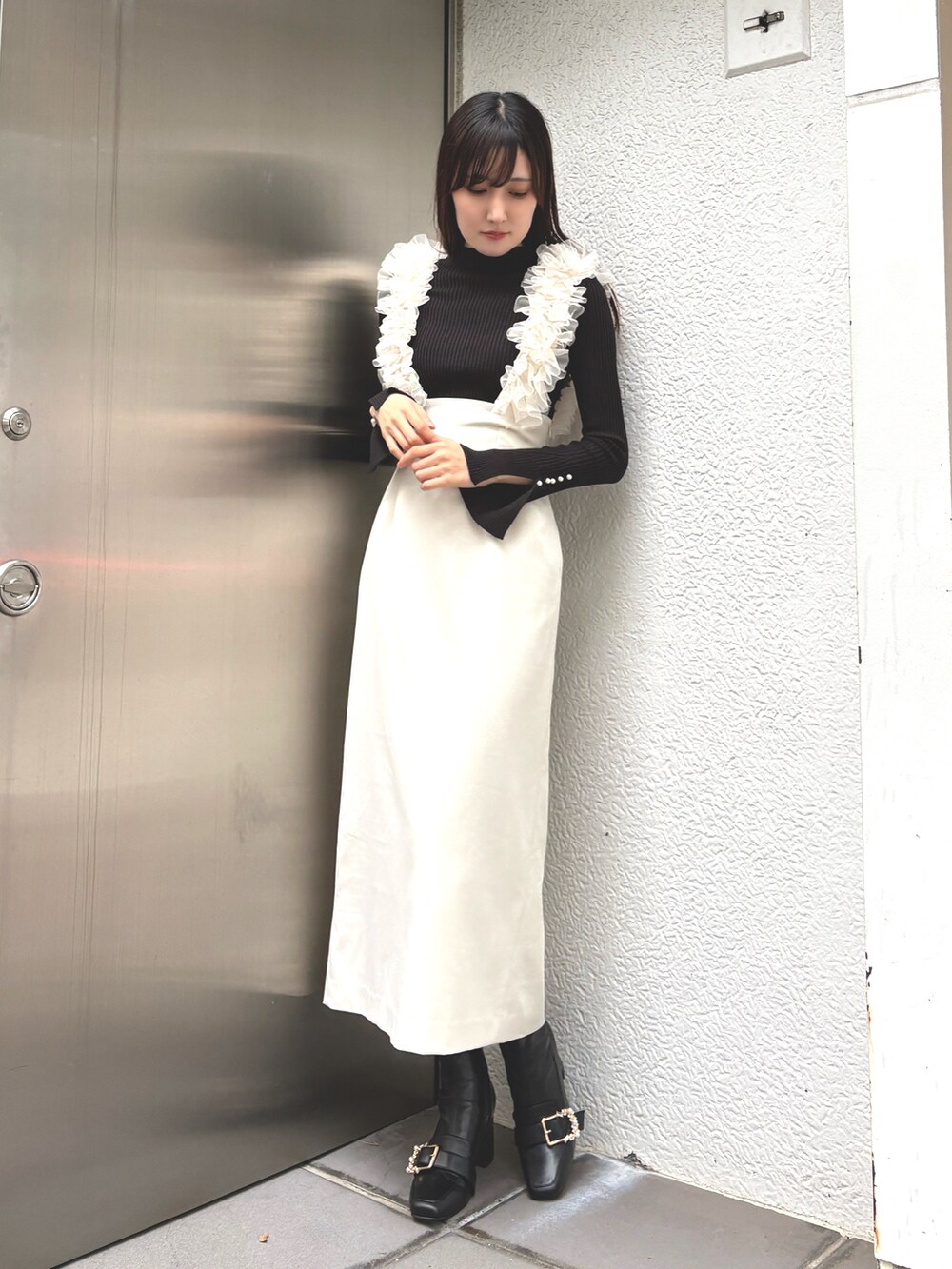 グレー系のニット/セーター、ホワイト系のスカート、ブラック系のブーツを着用したレディースの秋コーディネートの2枚目の写真