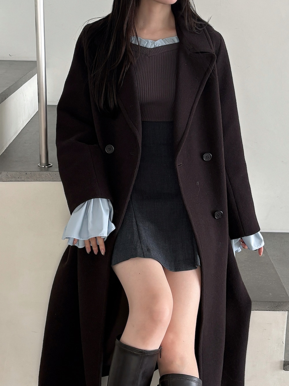 グレー系のニット/セーター、ブラウン系のチェスターコート、グレー系のスカートを着用したレディースの秋コーディネートの5枚目の写真