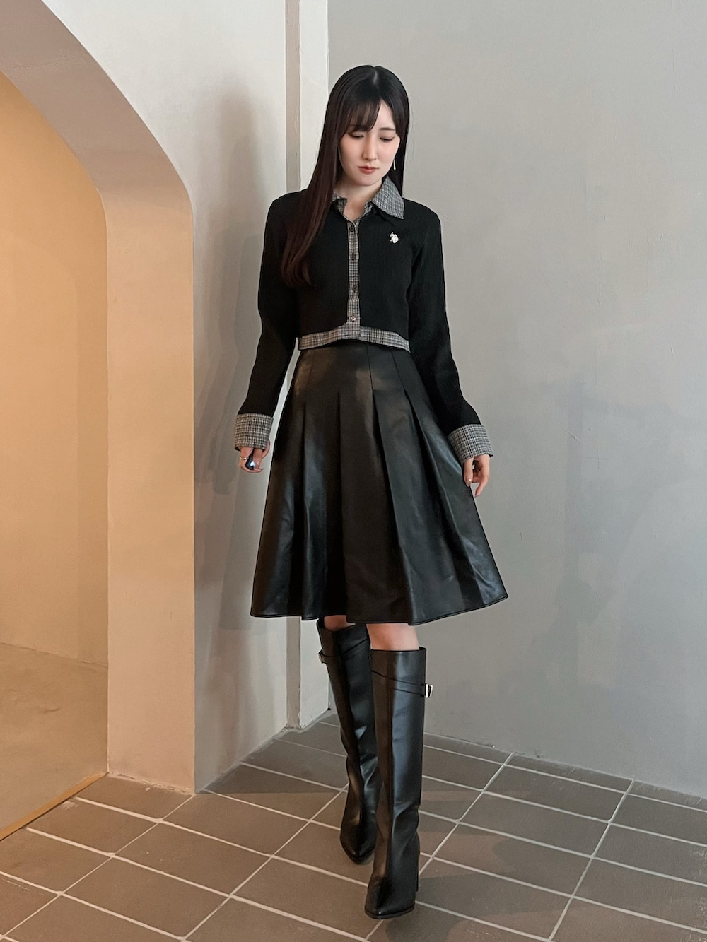 ブラック系のスカート、ブラック系のカーディガン/ボレロ、ブラック系のブーツを着用したレディースの秋コーディネートの2枚目の写真
