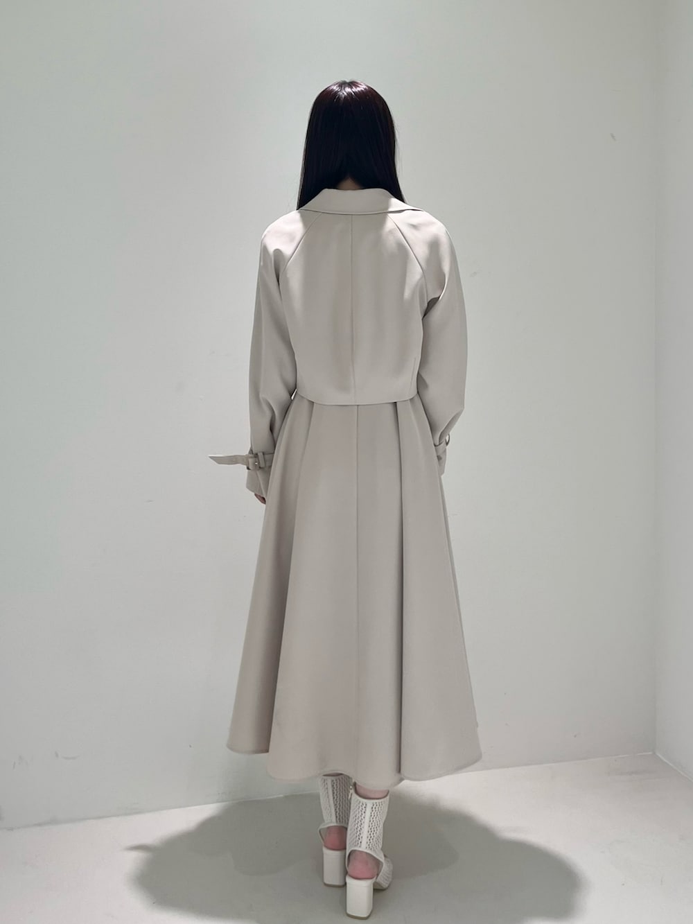 ホワイト系のブーツ、ベージュ系のトレンチコート、ベージュ系のワンピースを着用したレディースの冬コーディネートの5枚目の写真