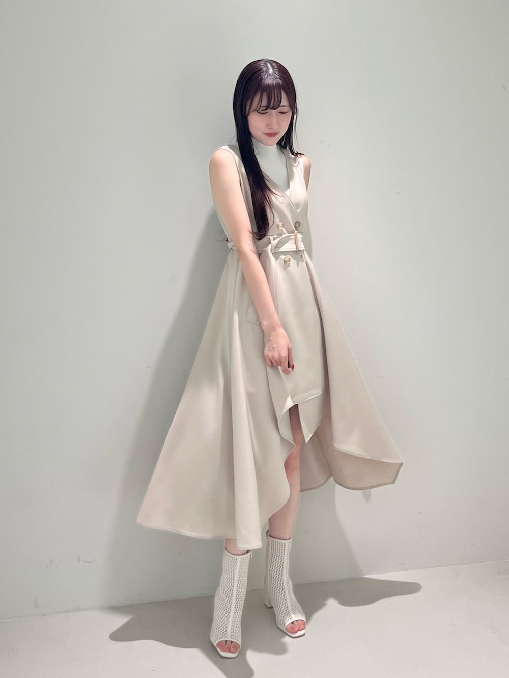 ベージュ系のワンピース、ホワイト系のブーツ、ホワイト系のニット/セーターを着用したレディースの春コーディネートの2枚目の写真