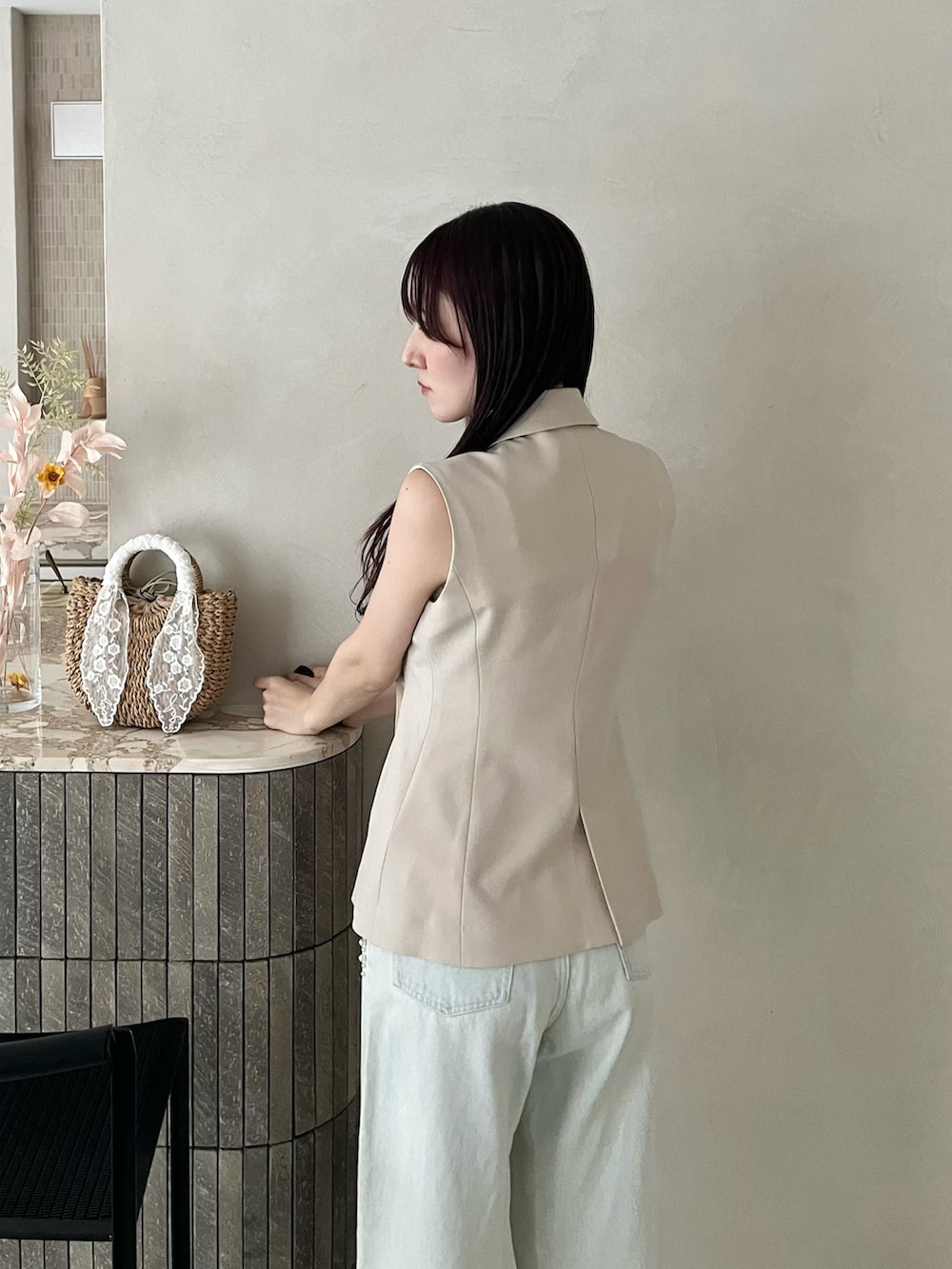 ブラック系のパンプス、ベージュ系のベスト、ブルー系のデニムパンツを着用したレディースの春コーディネートの5枚目の写真