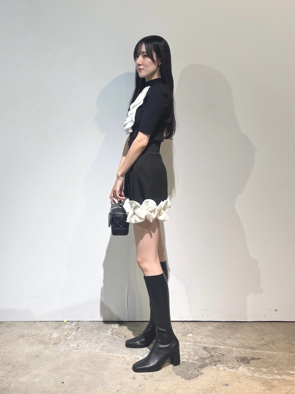 ブラック系のブーツ、ブラック系のニット/セーター、ブラック系のスカートを着用したレディースの秋コーディネートの4枚目の写真