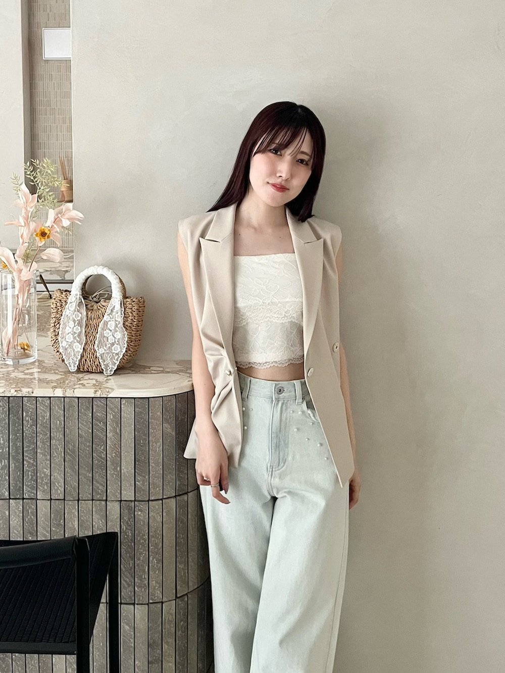 ブラック系のパンプス、ベージュ系のベスト、ブルー系のデニムパンツを着用したレディースの春コーディネートの4枚目の写真