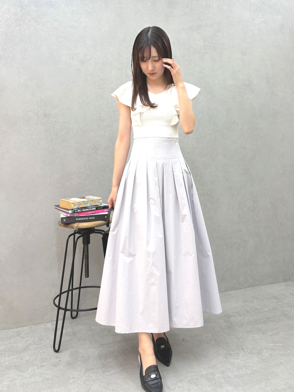 ブラック系のハンドバッグ、グレー系のスカート、ブラック系のパンプスを着用したレディースの夏コーディネートの2枚目の写真