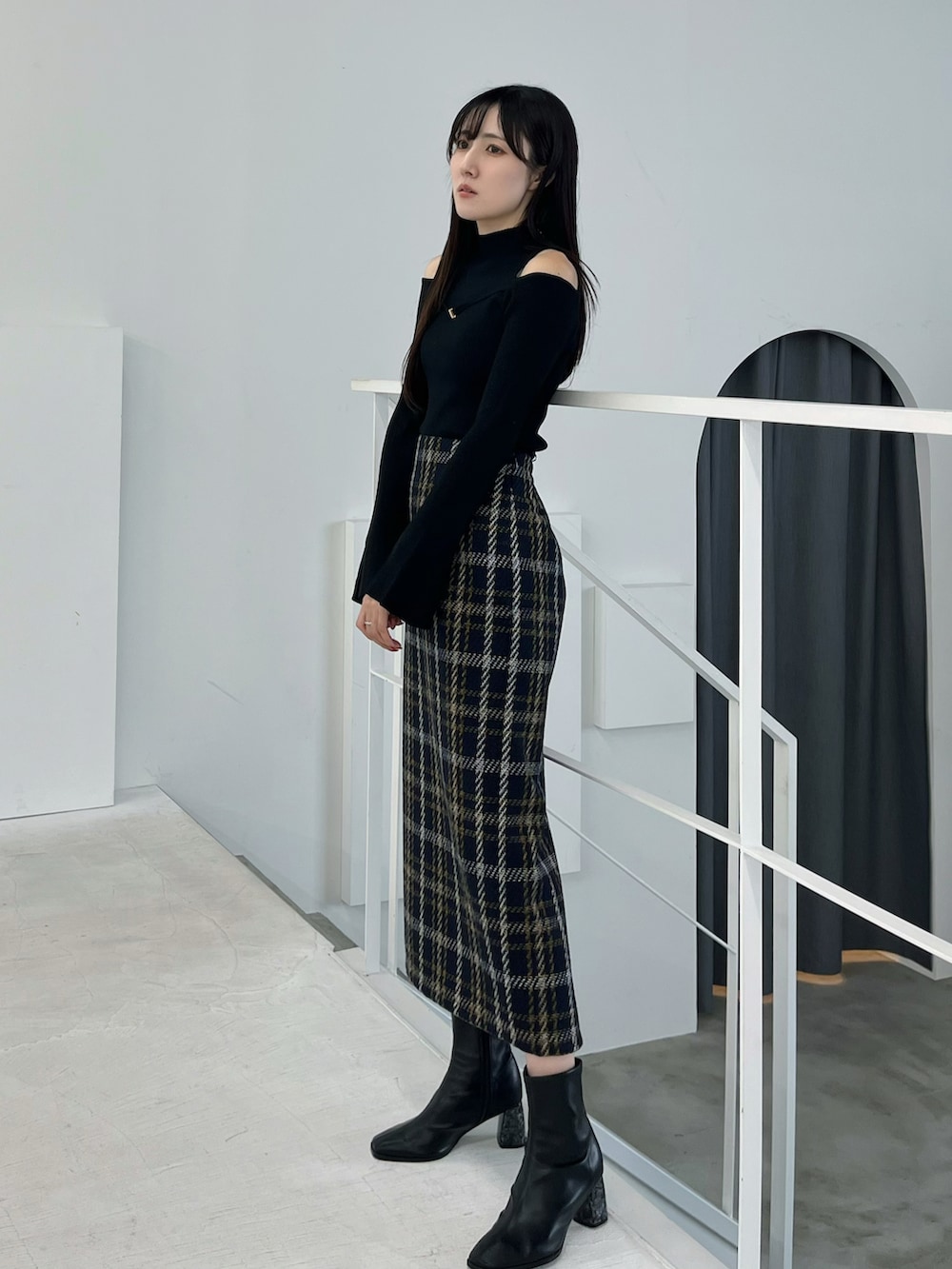 ブラック系のブーツ、ブルー系のスカート、ブラック系のニット/セーターを着用したレディースの春コーディネートの2枚目の写真