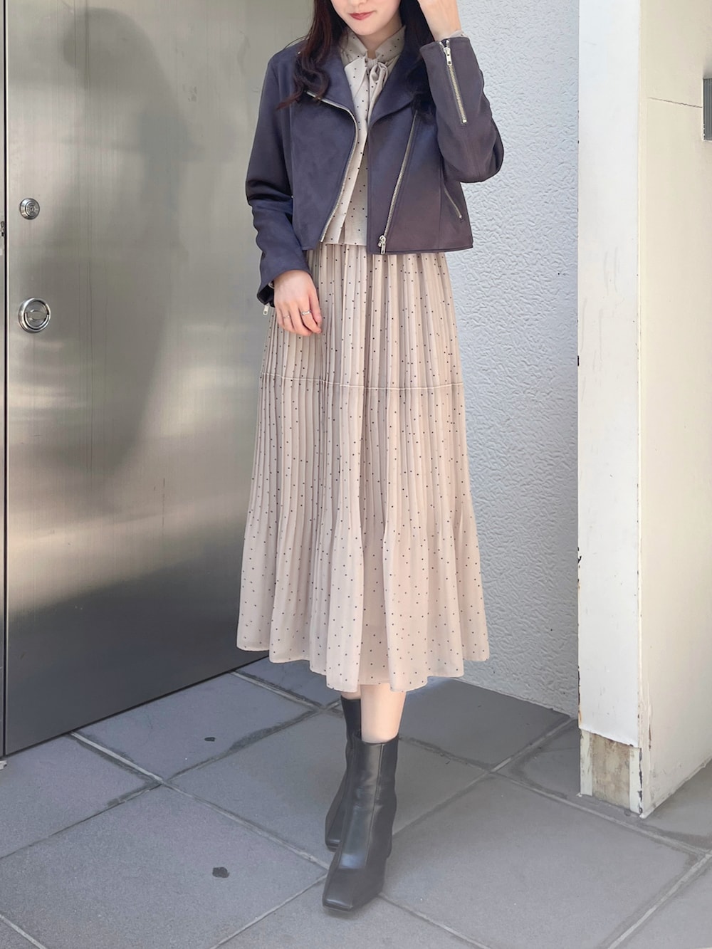 グレー系のライダースジャケット、ブラック系のブーツ、ベージュ系のワンピースを着用したレディースの秋コーディネートの2枚目の写真