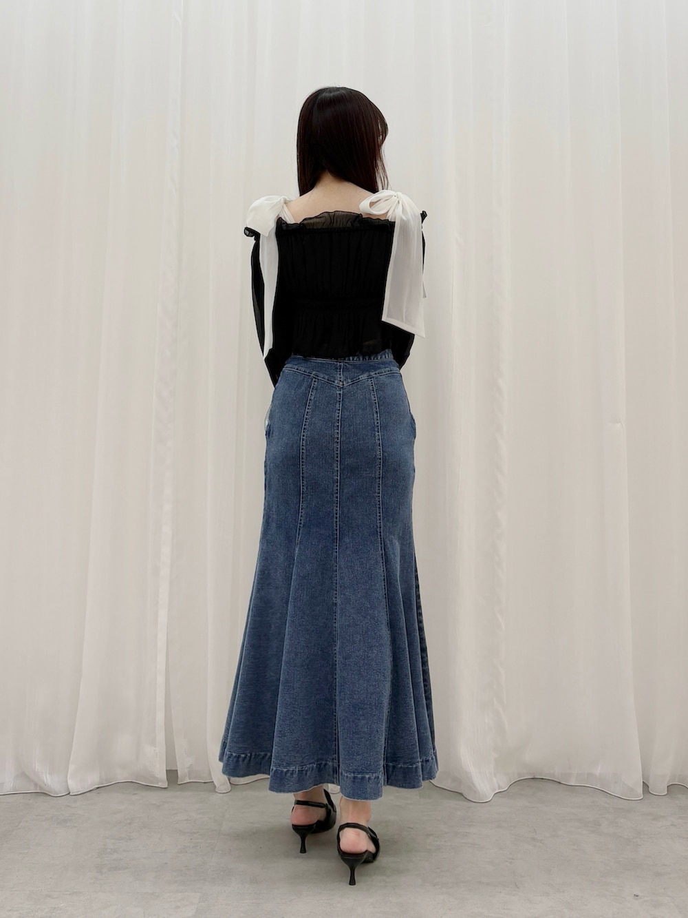 ブラック系のシャツ/ブラウス、ブルー系のスカート、ブラック系のパンプスを着用したレディースの春コーディネートの4枚目の写真