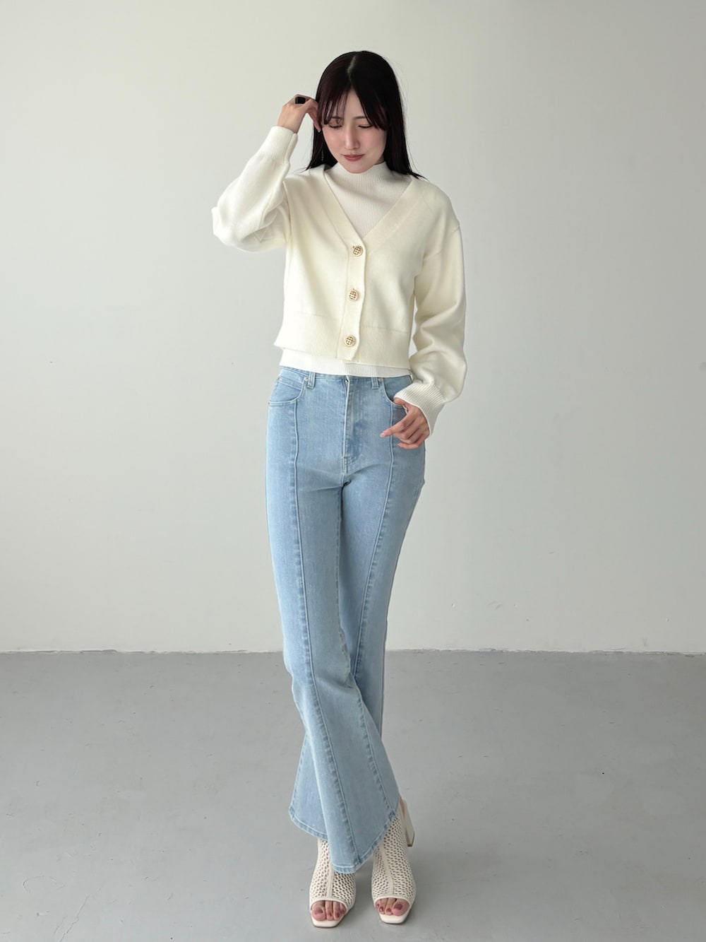 ホワイト系のカーディガン/ボレロ、ホワイト系のニット/セーター、ブルー系のデニムパンツを着用したレディースの冬コーディネートの2枚目の写真