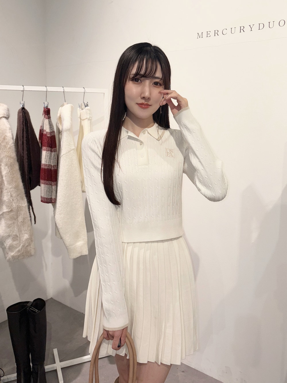 ベージュ系のハンドバッグ、ベージュ系のブーツ、ホワイト系のワンピースを着用したレディースの冬コーディネートの4枚目の写真