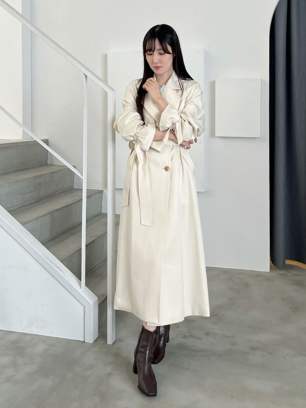 ブラウン系のブーツ、ホワイト系のトレンチコート、グリーン系のワンピースを着用したレディースの春コーディネートの3枚目の写真