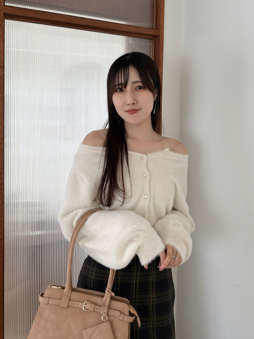 ホワイト系のカーディガン/ボレロ、ブラウン系のスカート、ベージュ系のハンドバッグを着用したレディースの秋コーディネートの4枚目の写真