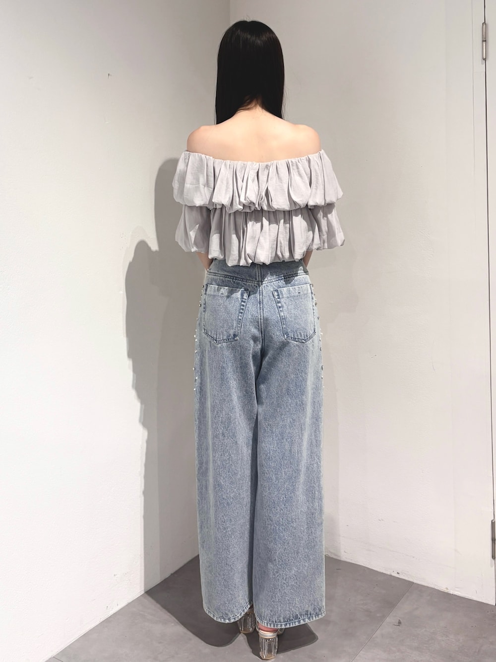 ブルー系のデニムパンツ、ベージュ系のハンドバッグ、シルバー系のサンダルを着用したレディースの夏コーディネートの4枚目の写真