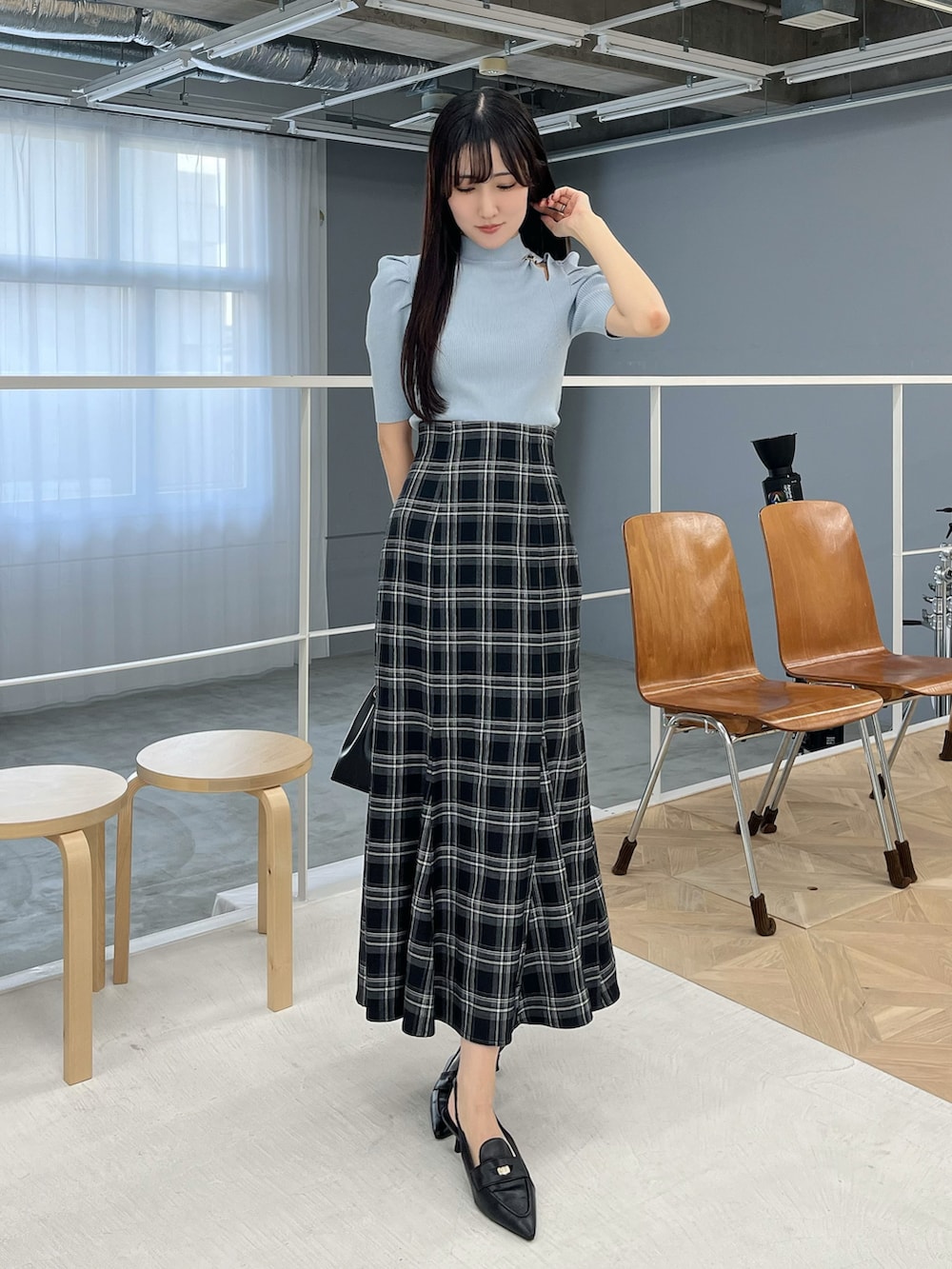 ブラック系のスカート、ブラック系のパンプス、ブルー系のニット/セーターを着用したレディースの春コーディネートの2枚目の写真