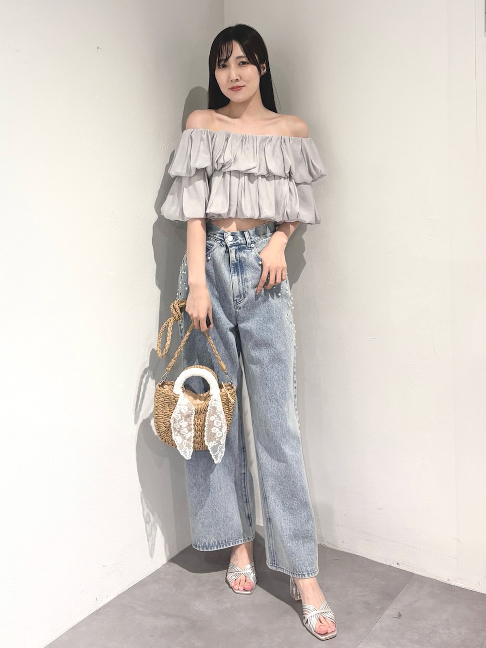 ブルー系のデニムパンツ、ベージュ系のハンドバッグ、シルバー系のサンダルを着用したレディースの夏コーディネートの2枚目の写真