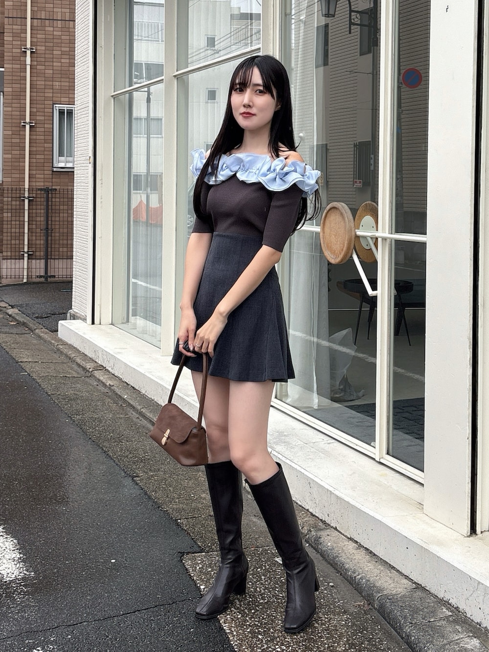 グレー系のニット/セーター、グレー系のスカート、ブラウン系のハンドバッグを着用したレディースの冬コーディネートの2枚目の写真