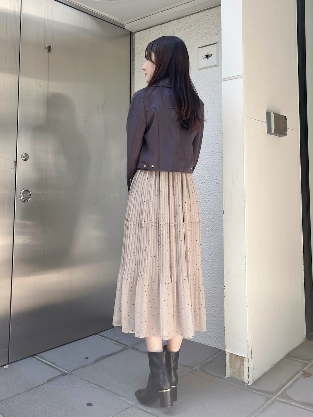 グレー系のライダースジャケット、ブラック系のブーツ、ベージュ系のワンピースを着用したレディースの秋コーディネートの3枚目の写真