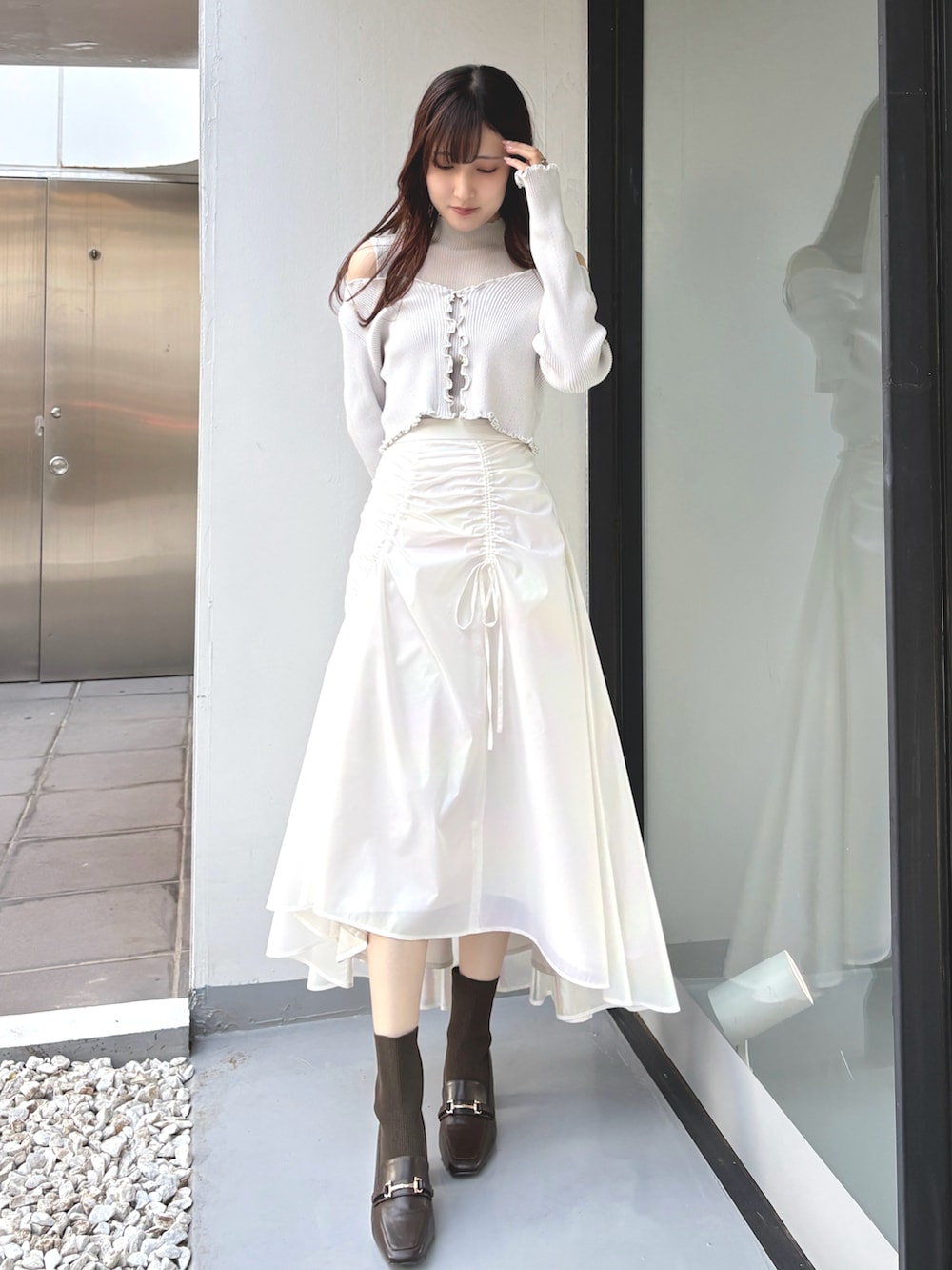 グレー系のカーディガン/ボレロ、グレー系のニット/セーター、ホワイト系のスカートを着用したレディースの冬コーディネートの2枚目の写真