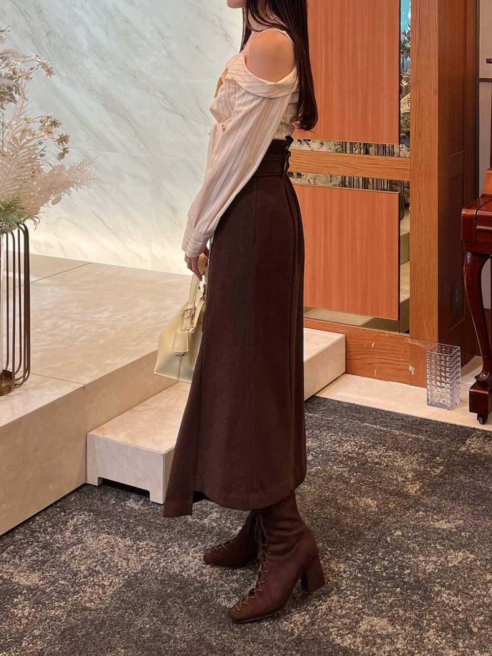 ブラウン系のブーツ、ブラウン系のスカート、イエロー系のショルダーバッグを着用したレディースの冬コーディネートの3枚目の写真