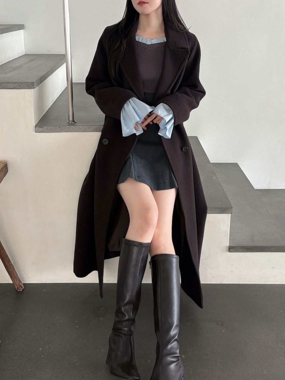 グレー系のニット/セーター、ブラウン系のチェスターコート、グレー系のスカートを着用したレディースの秋コーディネートの4枚目の写真