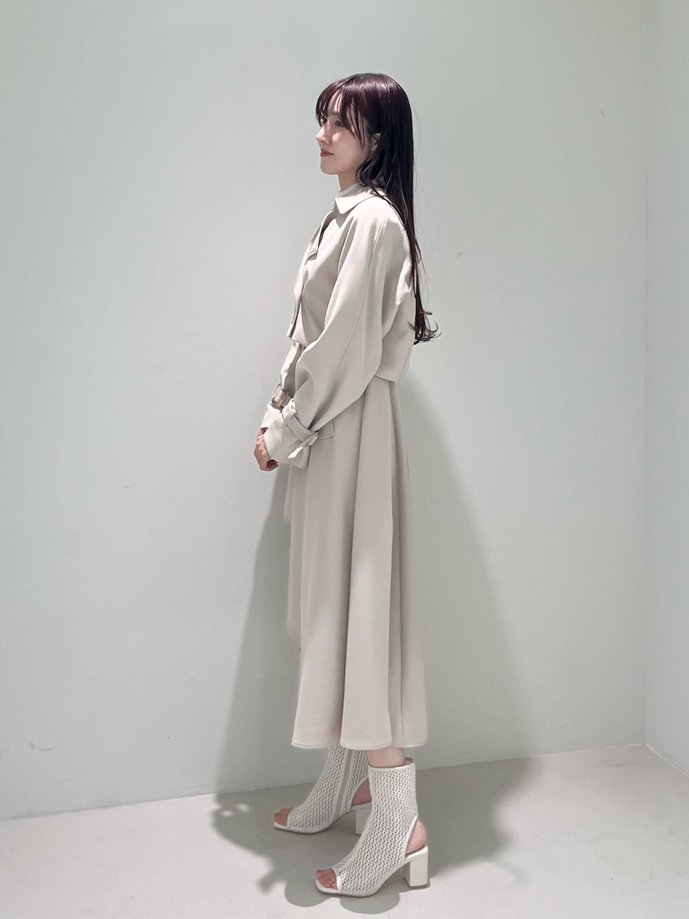 ホワイト系のブーツ、ベージュ系のトレンチコート、ベージュ系のワンピースを着用したレディースの冬コーディネートの4枚目の写真