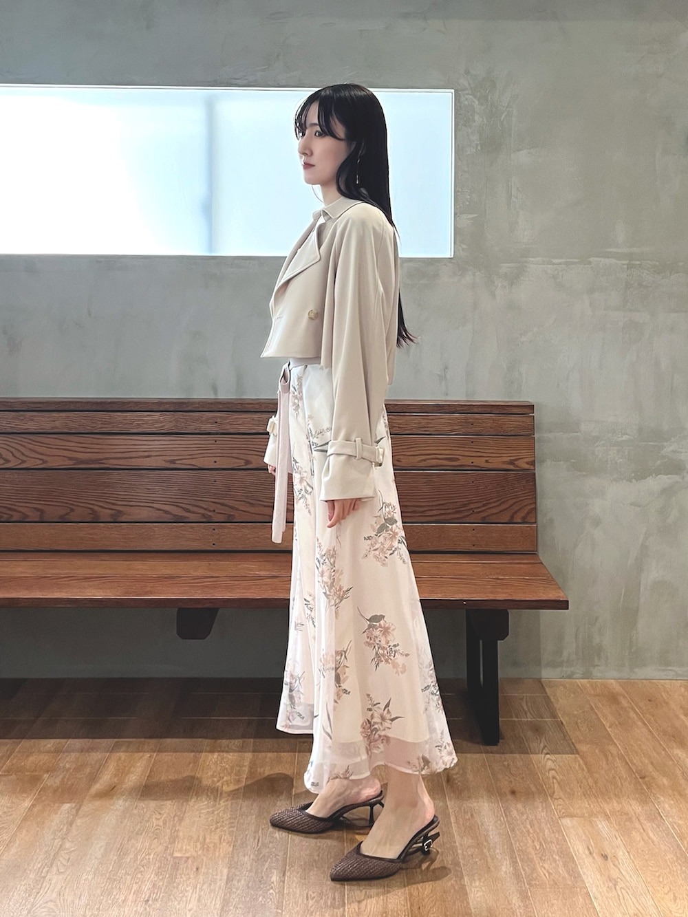 ブラウン系のパンプス、ベージュ系のワンピース、ホワイト系のトレンチコートを着用したレディースの春コーディネートの2枚目の写真
