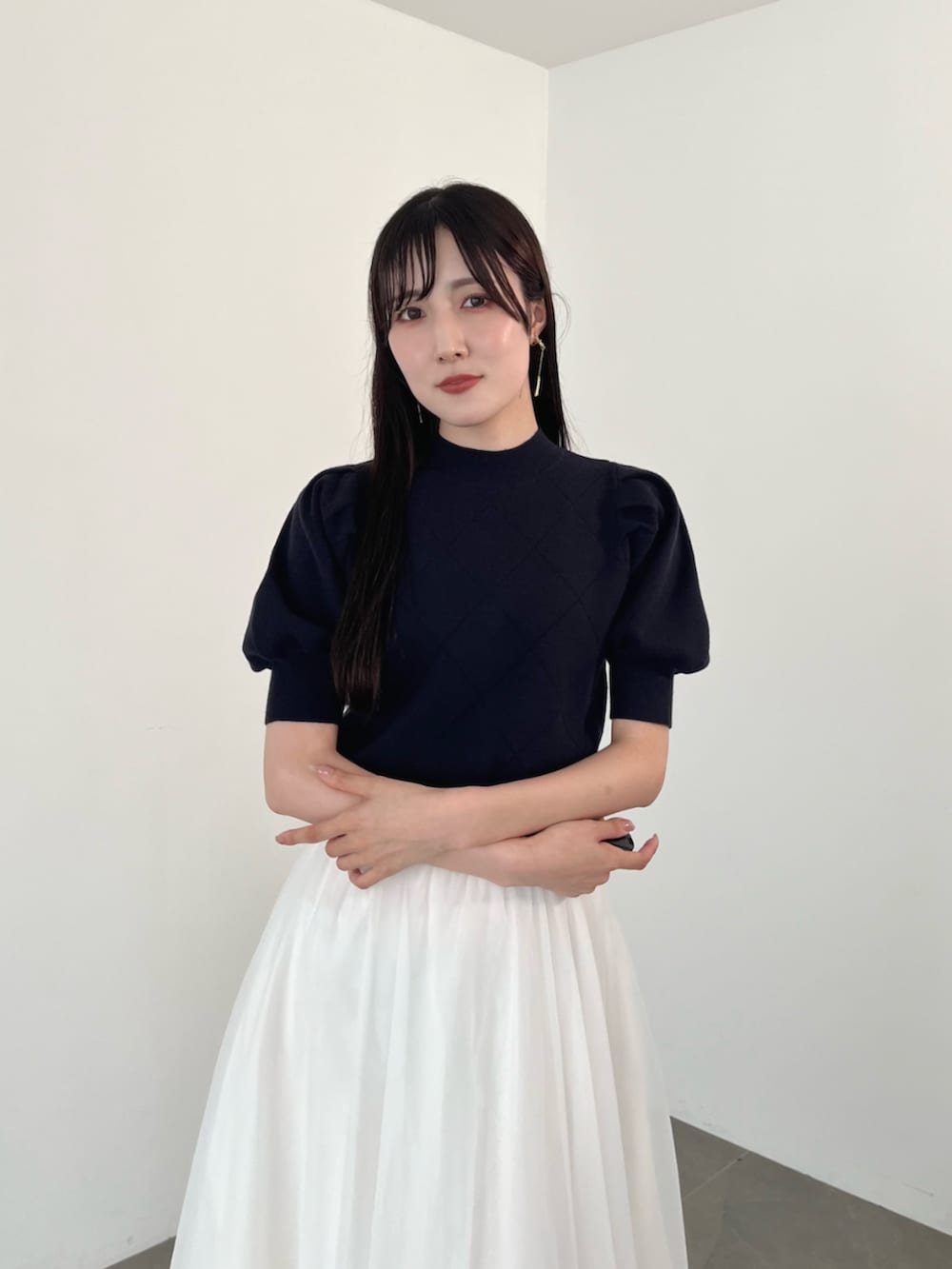 ブラック系のブーツ、ブルー系のニット/セーター、ホワイト系のスカートを着用したレディースの夏コーディネートの6枚目の写真