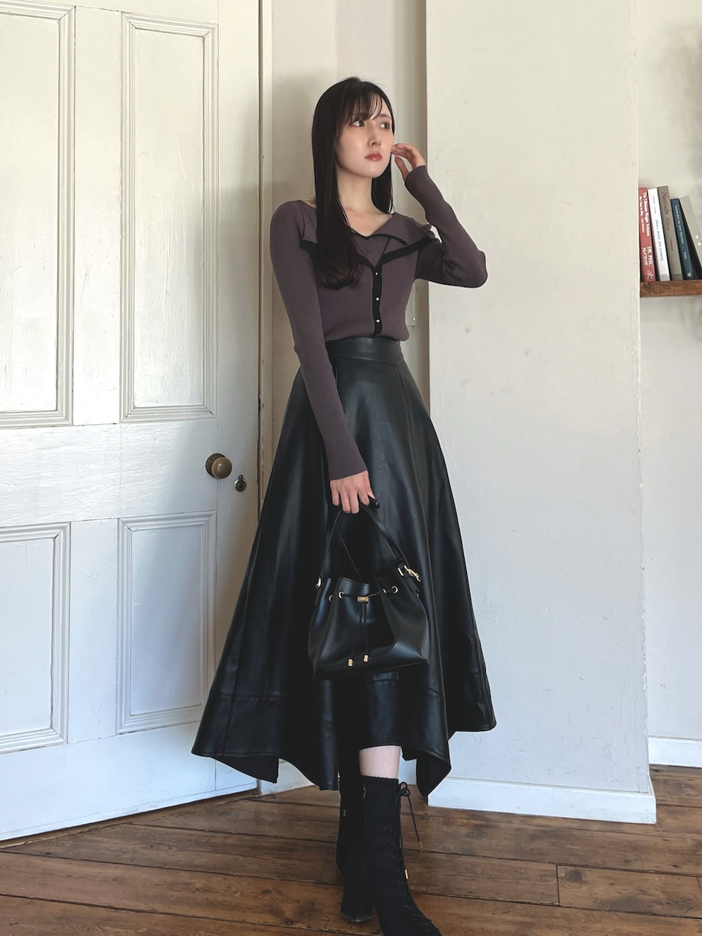 グレー系のニット/セーター、ブラック系のブーツ、ブラック系のショルダーバッグを着用したレディースの秋コーディネートの2枚目の写真