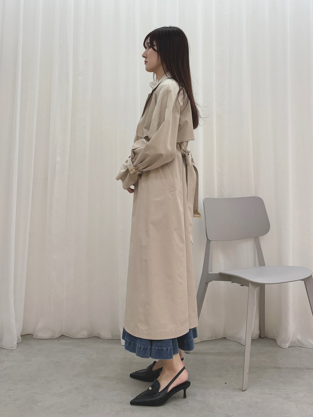 ベージュ系のトレンチコート、ブルー系のスカート、ブラック系のシャツ/ブラウスを着用したレディースの冬コーディネートの3枚目の写真