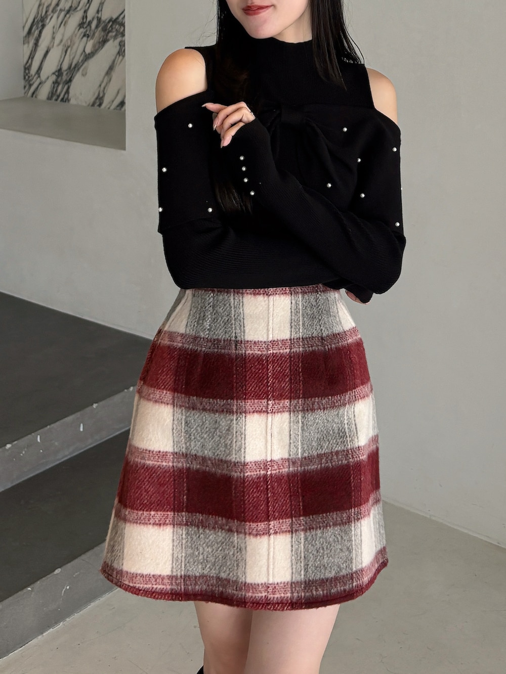 ブラック系のニット/セーター、レッド系のスカート、ブラウン系のブーツを着用したレディースの冬コーディネートの4枚目の写真