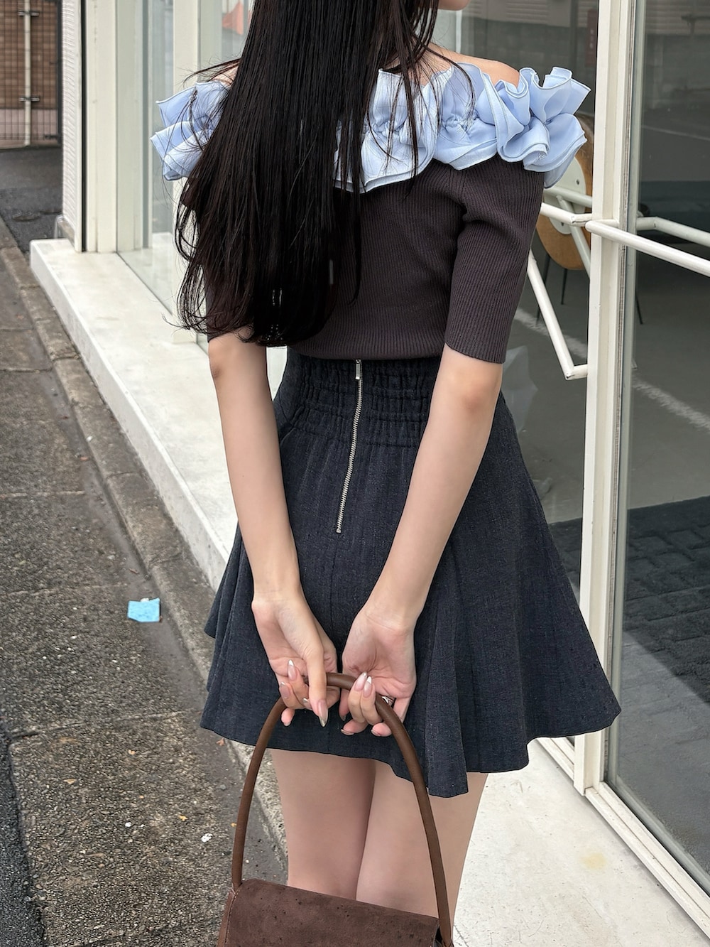 グレー系のニット/セーター、グレー系のスカート、ブラウン系のハンドバッグを着用したレディースの冬コーディネートの5枚目の写真