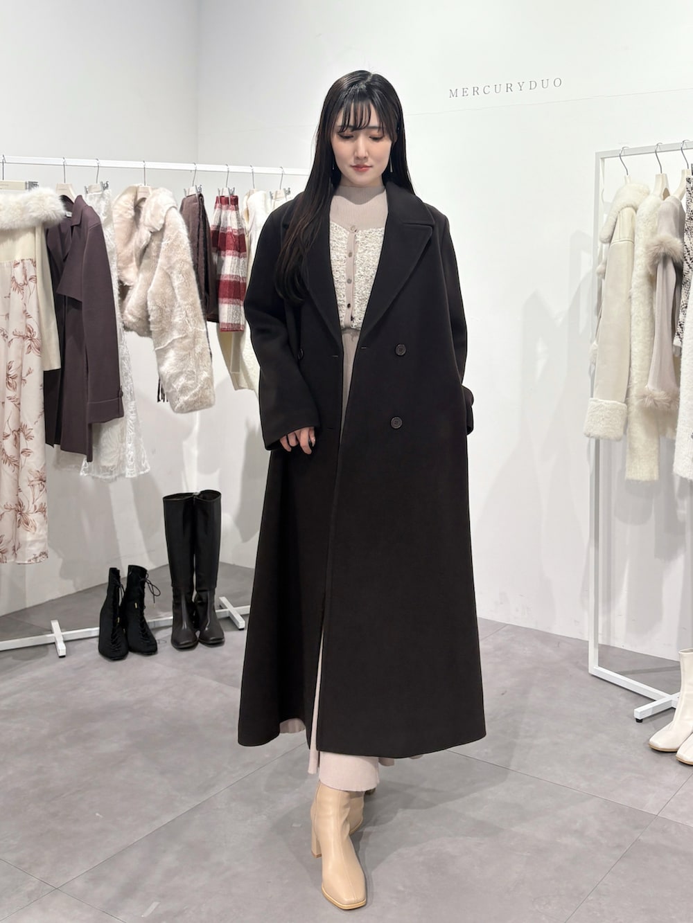 ブラウン系のチェスターコート、ピンク系のワンピース、ベージュ系のブーツを着用したレディースの冬コーディネートの2枚目の写真