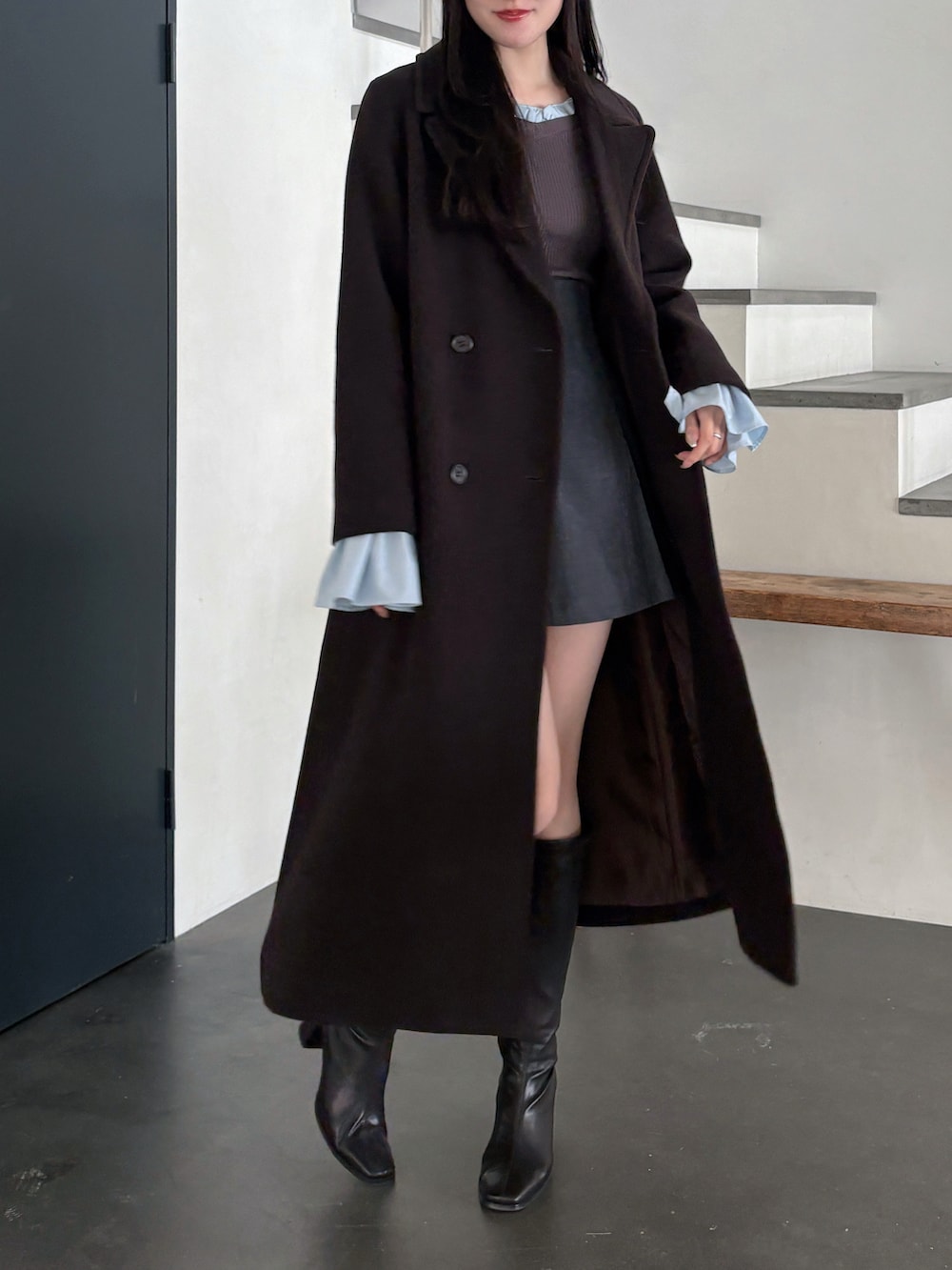 グレー系のニット/セーター、ブラウン系のチェスターコート、グレー系のスカートを着用したレディースの秋コーディネートの3枚目の写真