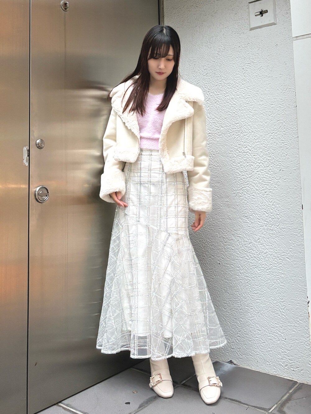 ピンク系のニット/セーター、ベージュ系のムートンコート、ホワイト系のスカートを着用したレディースの冬コーディネートの2枚目の写真