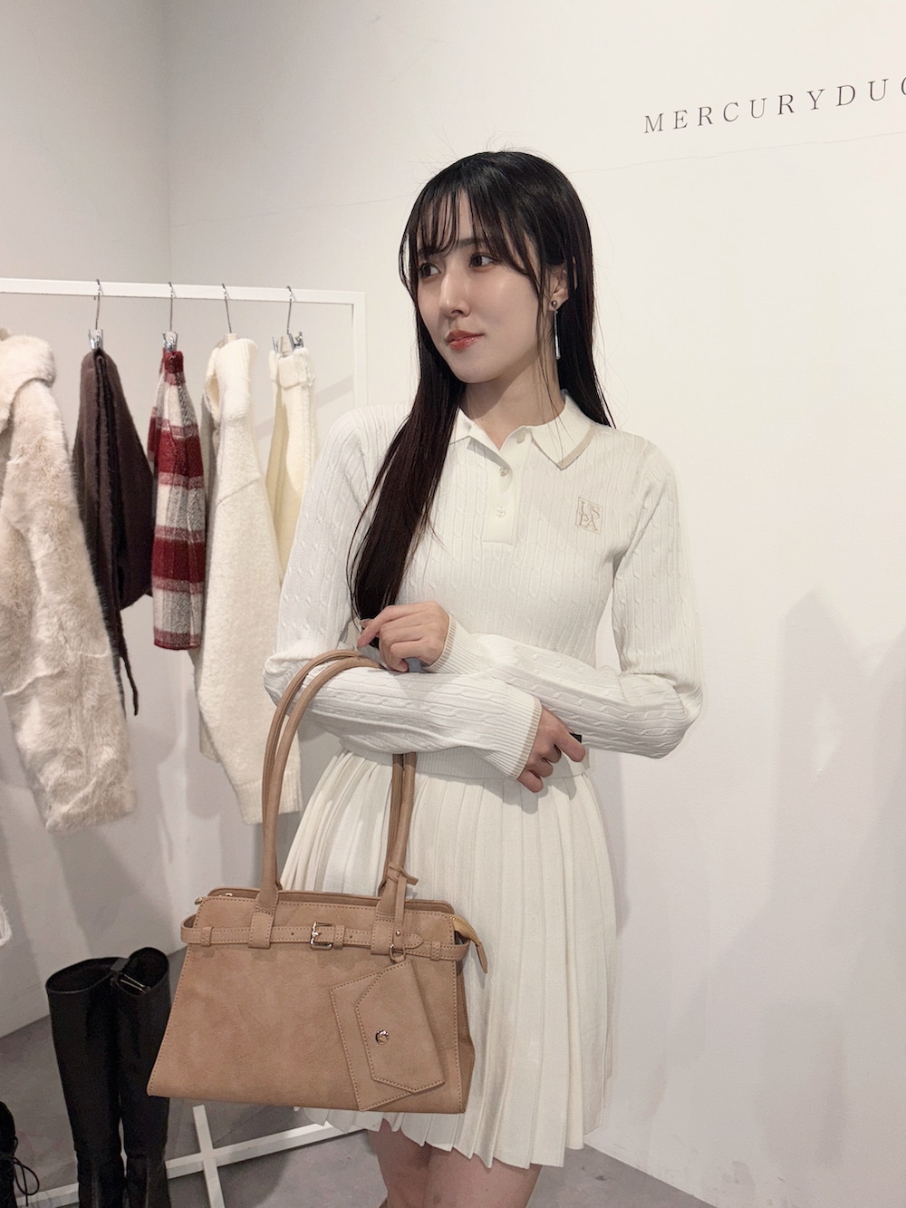 ベージュ系のハンドバッグ、ベージュ系のブーツ、ホワイト系のワンピースを着用したレディースの冬コーディネートの5枚目の写真