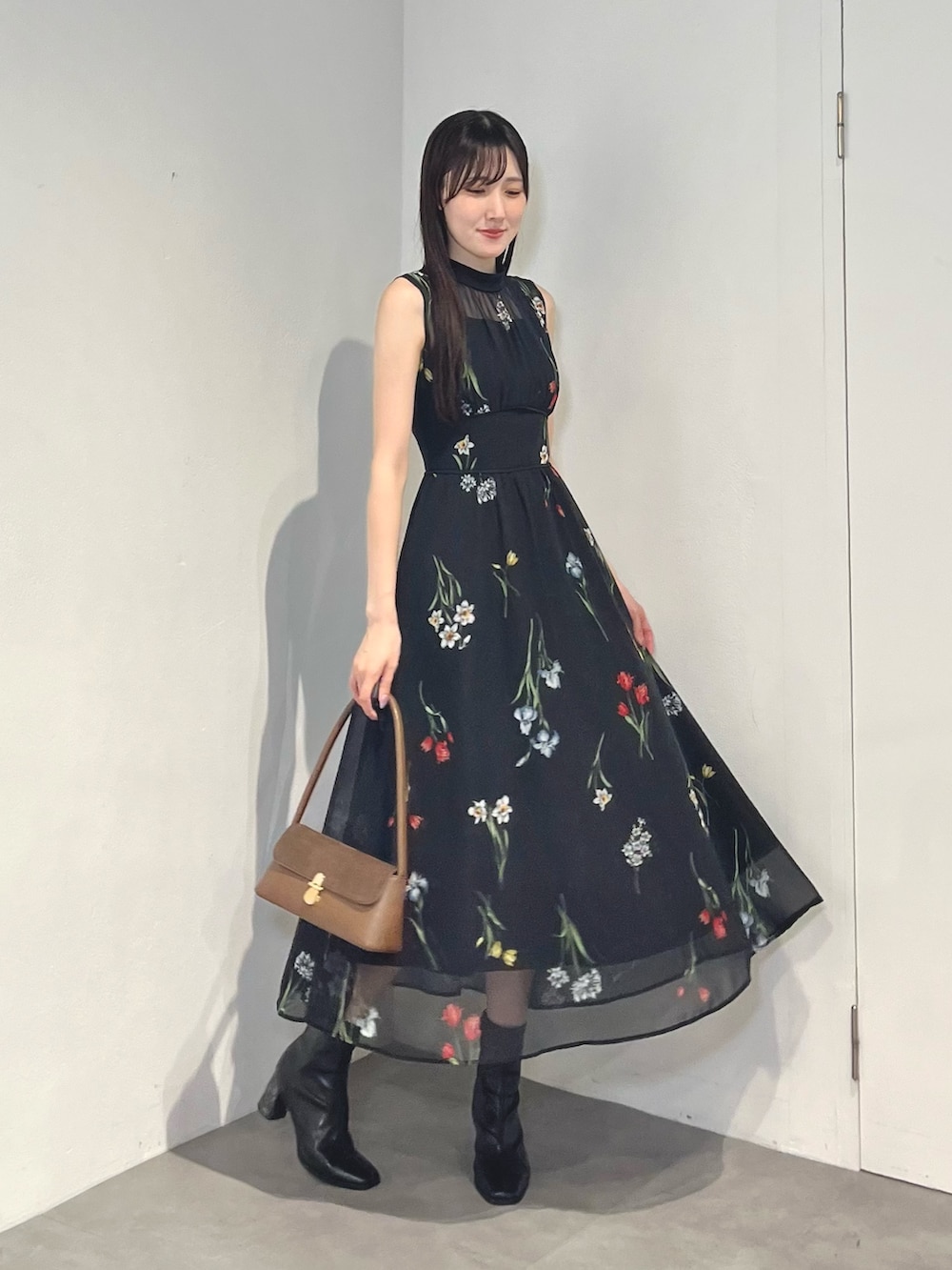 ブラック系のブーツ、ブラック系のワンピース、ホワイト系のハンドバッグを着用したレディースの夏コーディネートの2枚目の写真