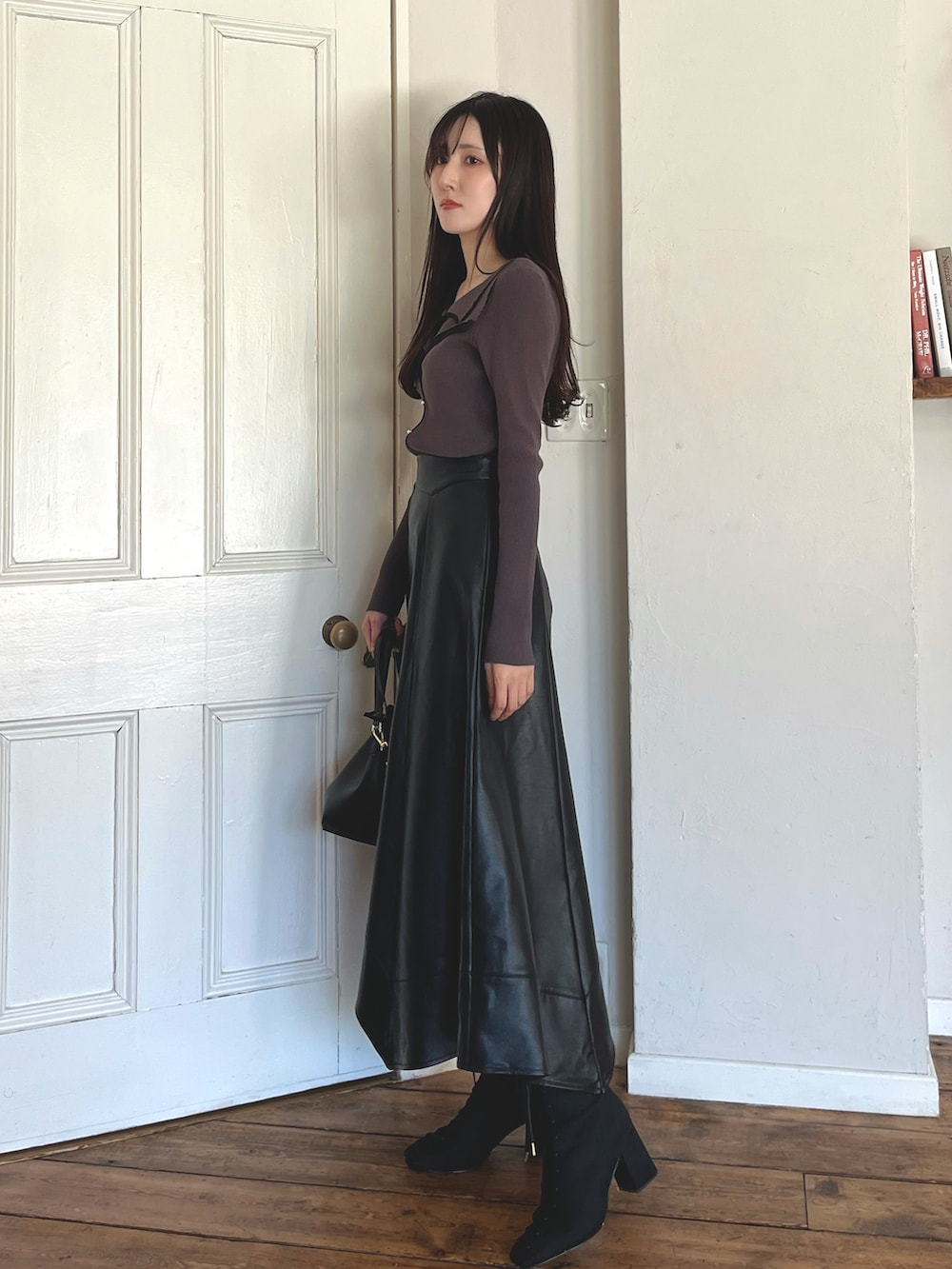 グレー系のニット/セーター、ブラック系のブーツ、ブラック系のショルダーバッグを着用したレディースの秋コーディネートの3枚目の写真