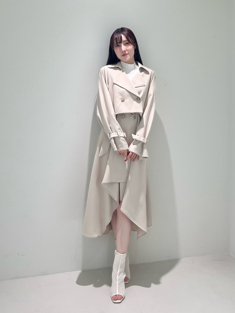ホワイト系のブーツ、ベージュ系のトレンチコート、ベージュ系のワンピースを着用したレディースの冬コーディネートの2枚目の写真