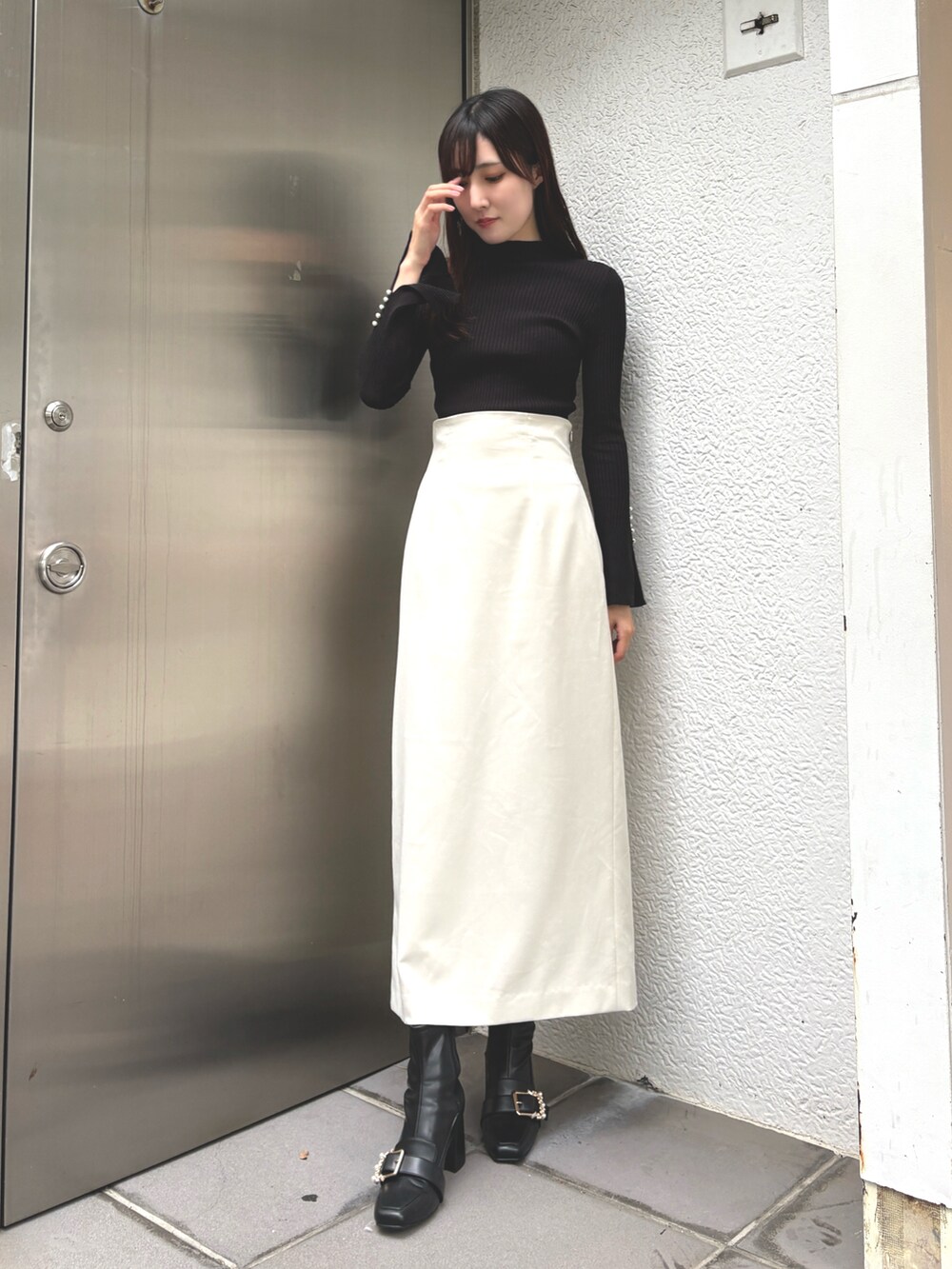 グレー系のニット/セーター、ホワイト系のスカート、ブラック系のブーツを着用したレディースの秋コーディネートの3枚目の写真