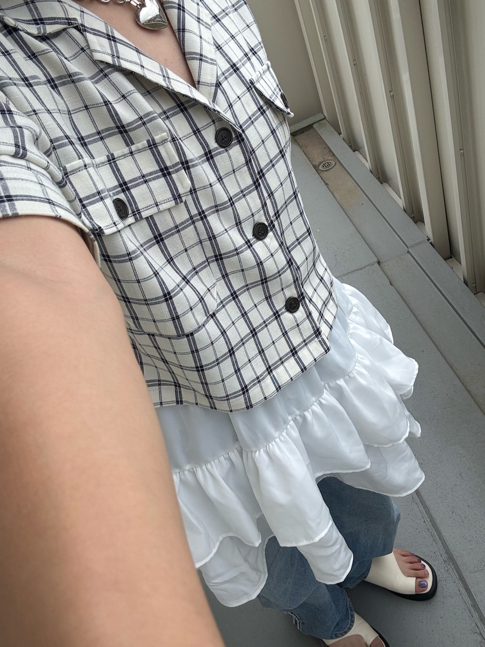 ホワイト系のサンダル、ブルー系のデニムパンツ、ホワイト系のスカートを着用したレディースの夏コーディネートの2枚目の写真