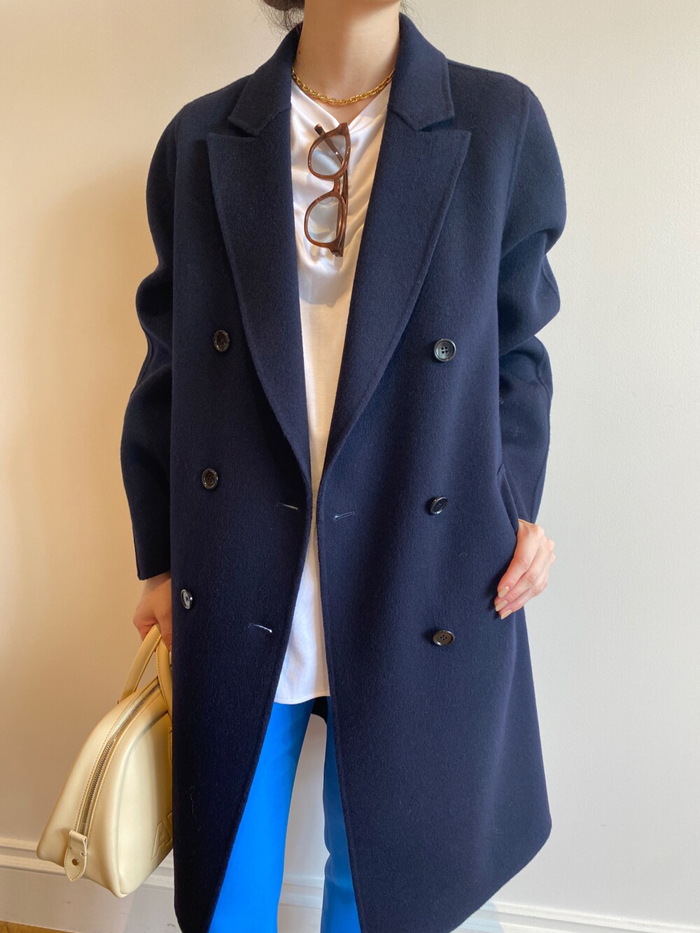 ホワイト系のTシャツ/カットソー、ブルー系のチェスターコート、イエロー系のボストンバッグを着用したレディースの秋コーディネートの3枚目の写真