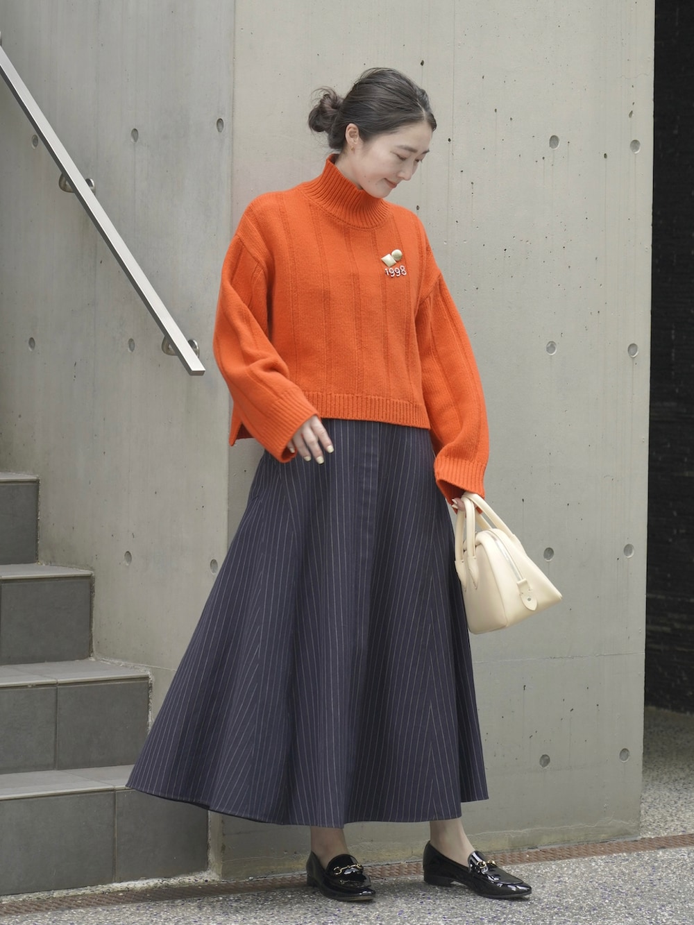 ブルー系のワンピース、オレンジ系のニット/セーター、ブラック系のローファーを着用したレディースの秋コーディネートの2枚目の写真