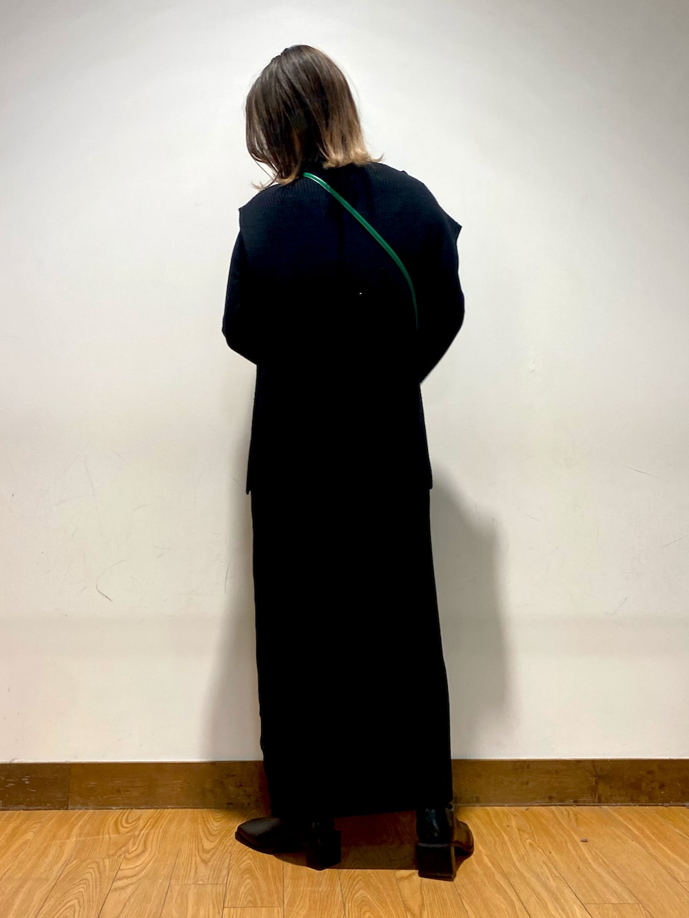 ブラック系のワンピース、グリーン系のショルダーバッグ、ブラック系のブーツを着用したレディースの冬コーディネートの2枚目の写真